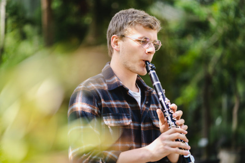 Musikerportrait: Burkard Euring spielt Klarinette mit vielen Pflanzen im Hintergrund