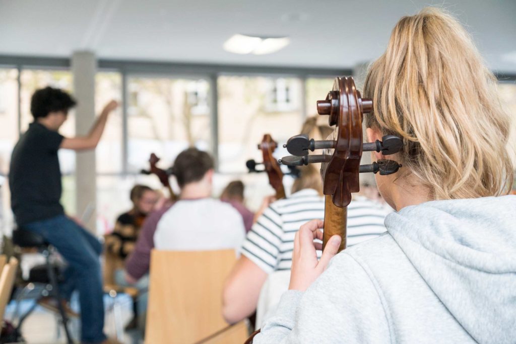 Blick über die Schulter einer Cellistin in der Orchesterprobe der Jungen Philharmonie Würzburg