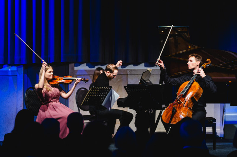 Konzertfotografie: Drei Musiker auf der Bühne strecken die Hände beim Schlusston